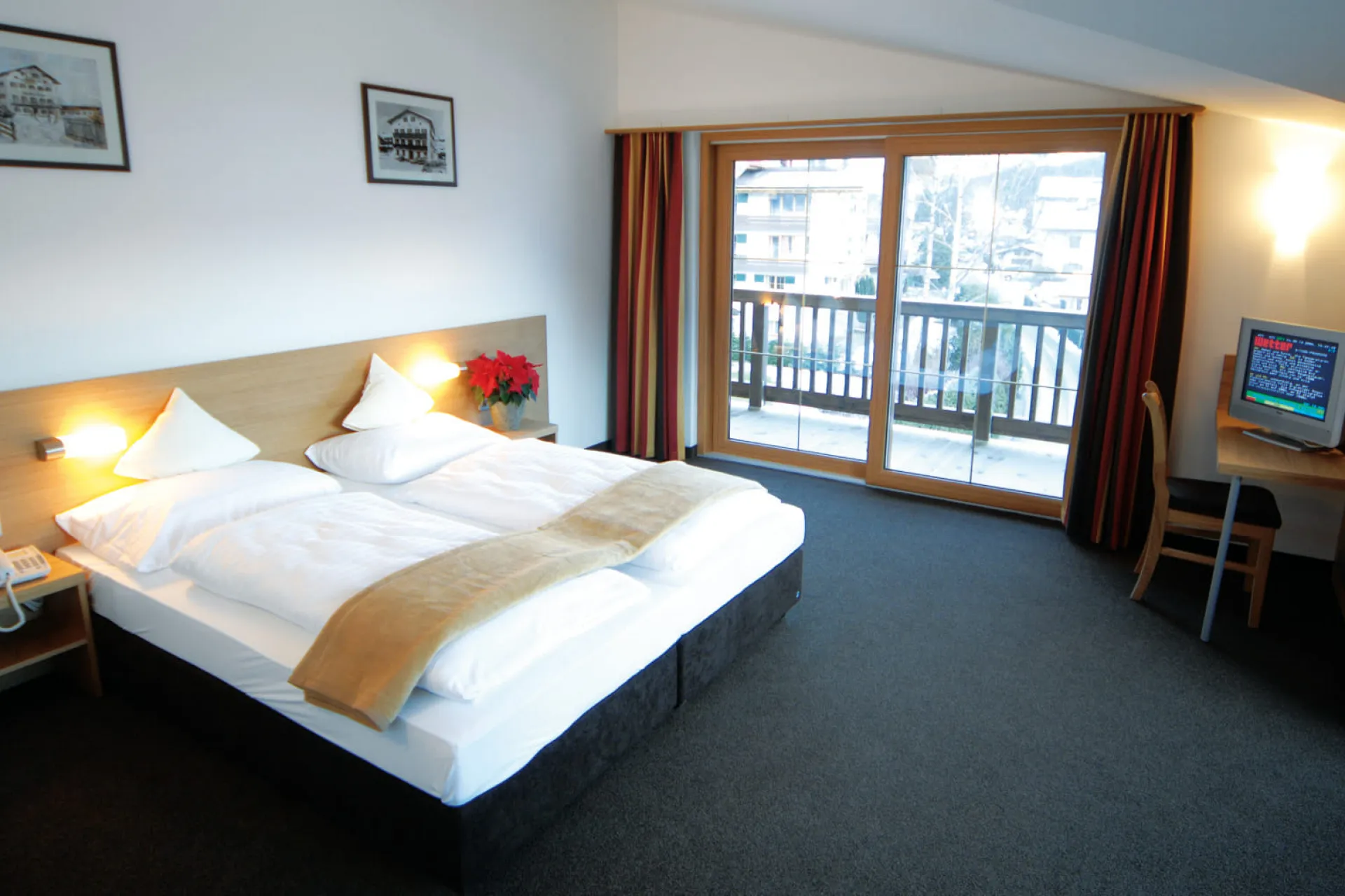 helles Hotelzimmer mit zwei Betten, Balkon und Schreibtisch