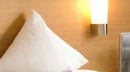 Kissen und Nachtlampe an einer Wand mit Holzpaneel