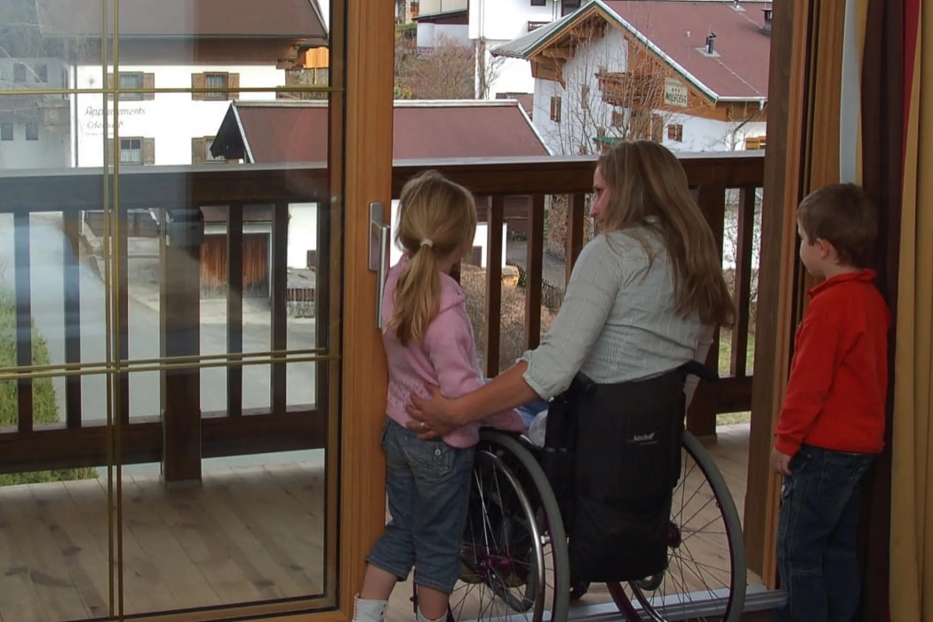 Familie im Rollstuhl blickt auf den Balkon mit Blick auf das Wasser