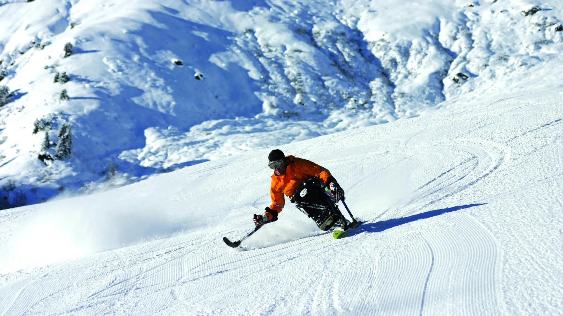 Skifahrer im Sitzen auf verschneiter Piste mit Berglandschaft im Hintergrund