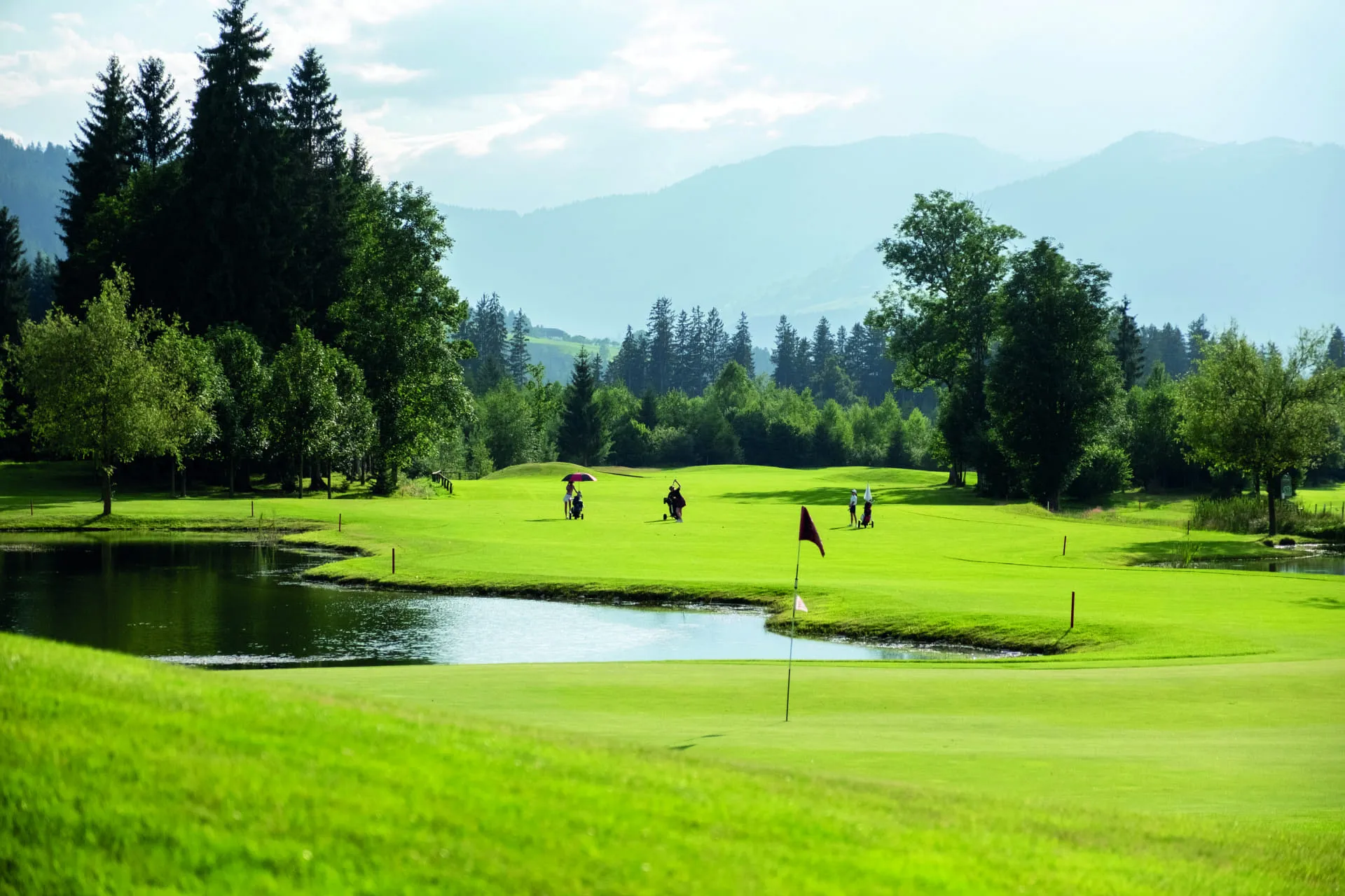 Golfplatz im Brixental mit Bäumen und Bergen im Hintergrund