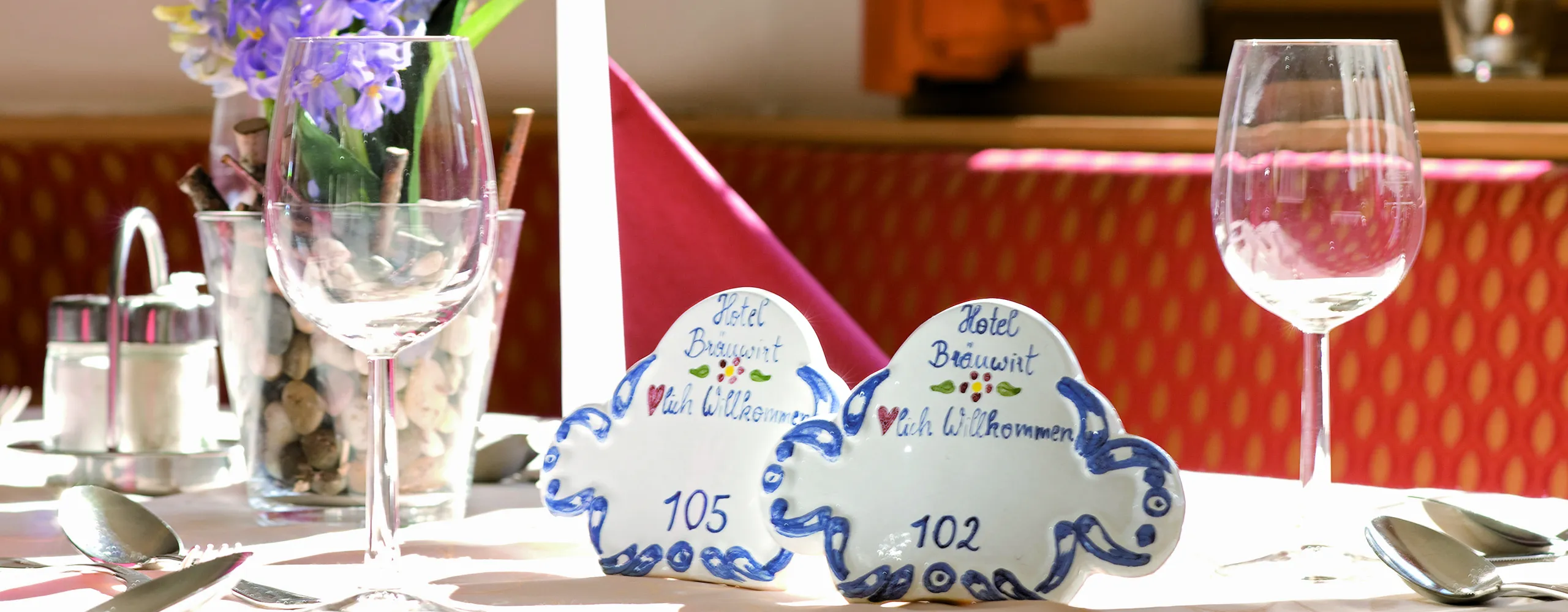 Tisch mit Gläsern, Blumen und Platzkarten bei Sonnenlicht