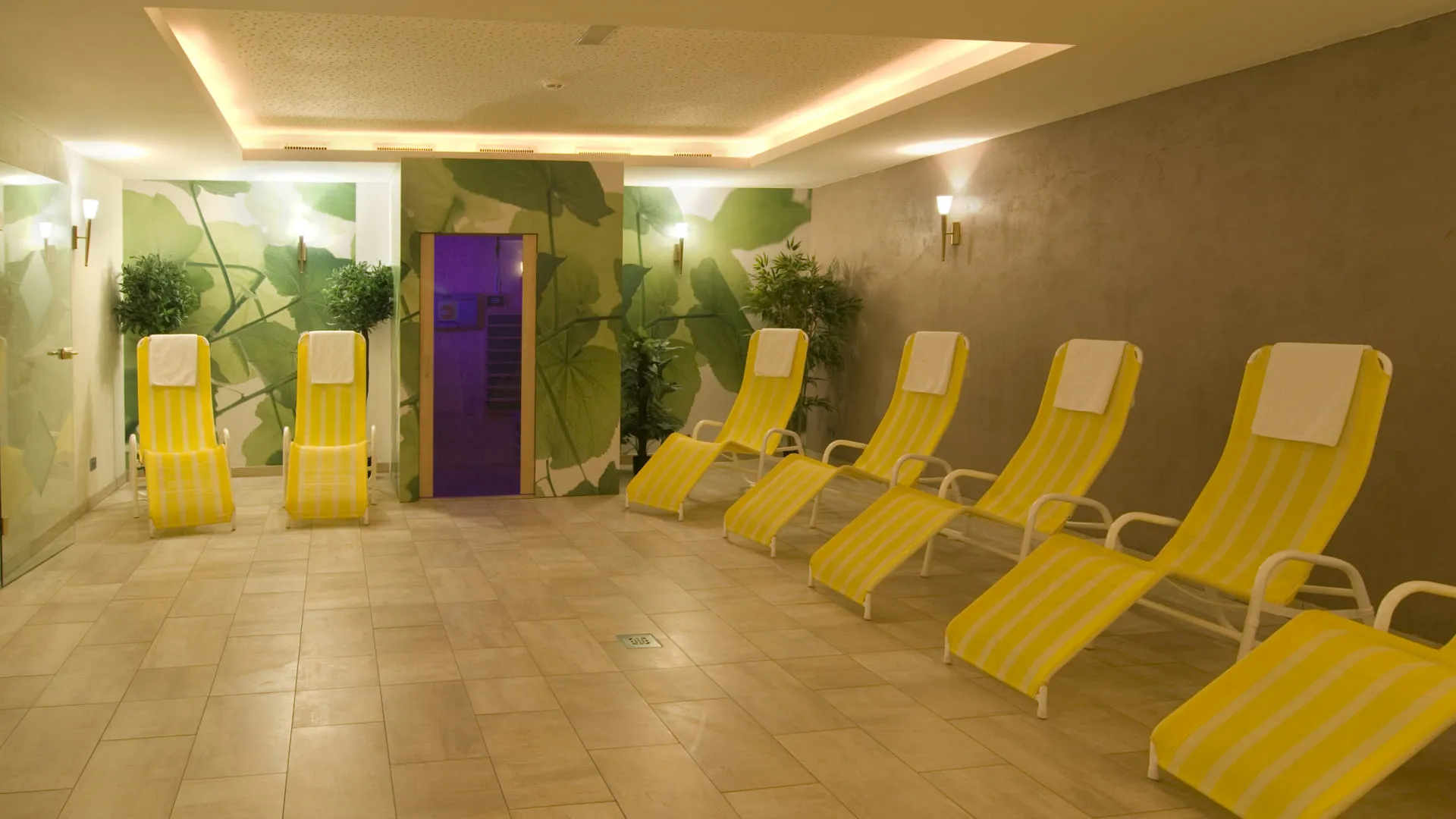 Ruhiger Spa-Bereich mit gelben Liegen und modernen Wandmalereien.