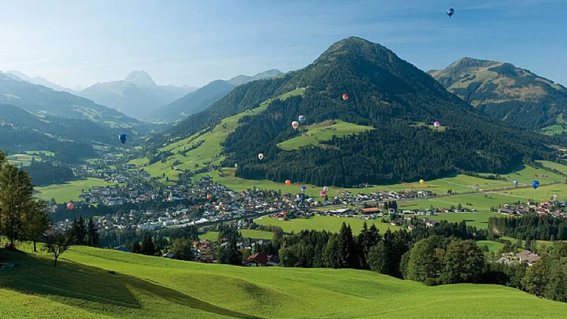 Landschaft mit Bergen, Wiesen und Luftballons über Kirchberg